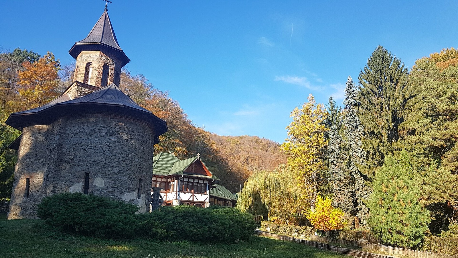 Biserica și casele mănăstirii pe fundalul pădurii